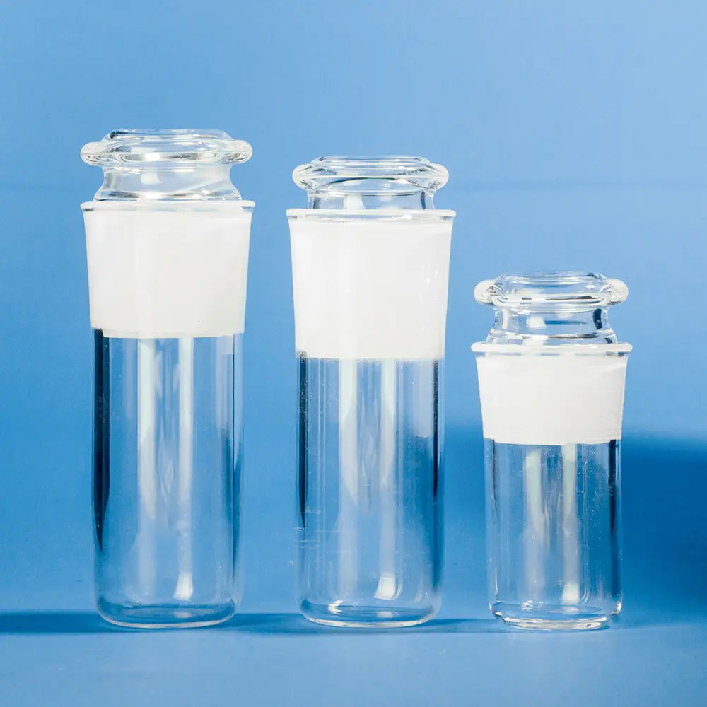 Three flat bottom frosted quartz test tubes with clear bodies and frosted plugs, varying in size, presented against a bright blue background