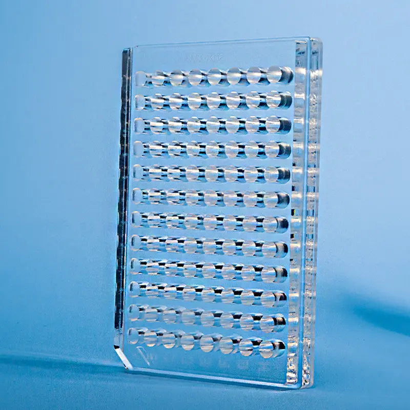 Transparent quartz 96 well plate with spherical wells on a blue background.