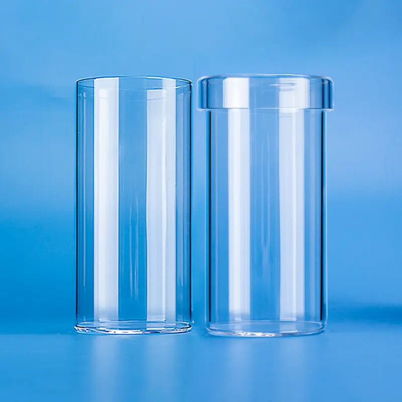 Two clear quartz straight cylindrical crucibles/beakers of different heights, showcasing their transparent appearance and smooth finish on a blue background
